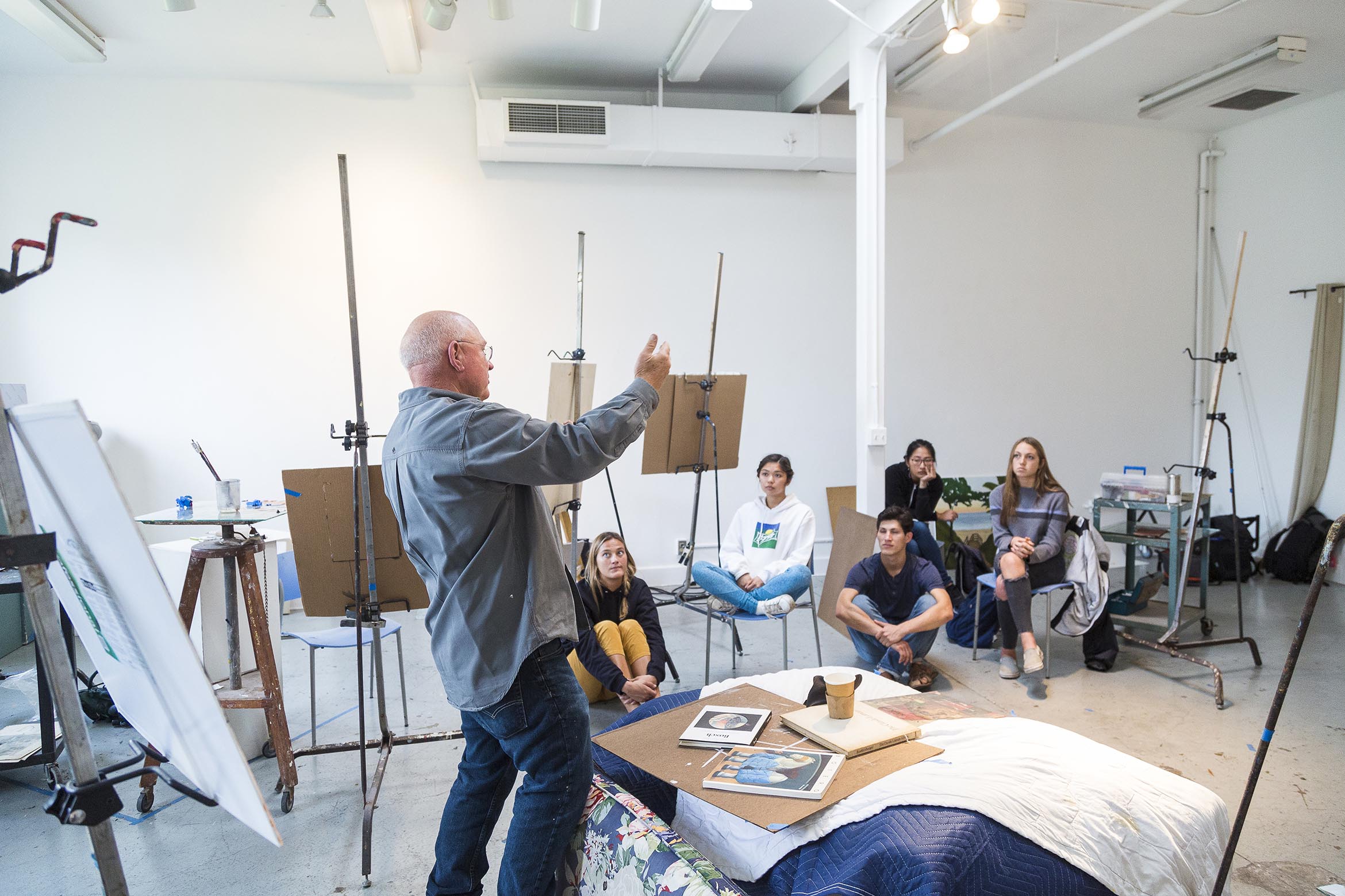 This is an art professor lecturing to his class in a studio.