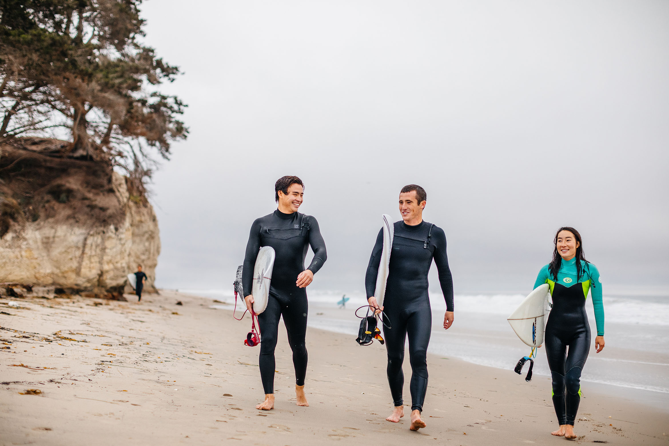 This is an image of three student surfers on the beach.